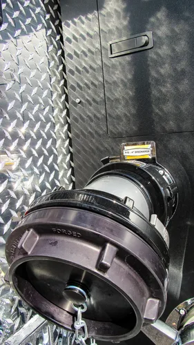 Exterior view of small fire truck showing cab, body compartments, and wheel/tire area.