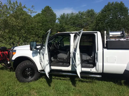 Exterior view of small fire truck showing cab, body compartments, and wheel/tire area.