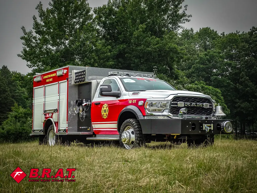 Exterior view of small fire truck showing cab, body compartments, and wheel/tire area.