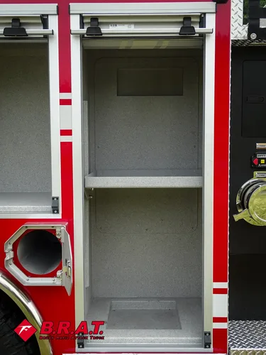 Exterior view of small fire truck showing cab, body compartments, and wheel/tire area.