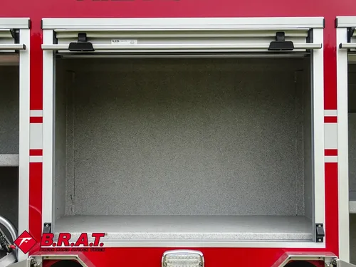 Exterior view of small fire truck showing cab, body compartments, and wheel/tire area.