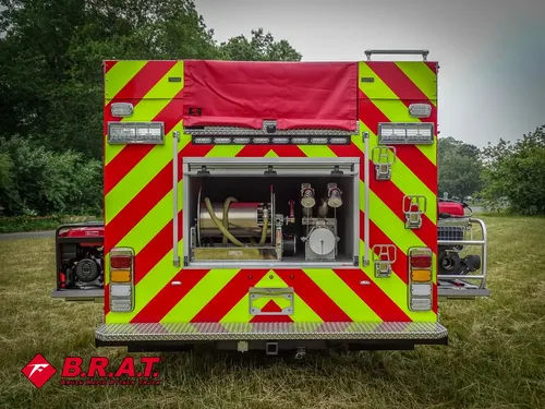 Exterior view of small fire truck showing cab, body compartments, and wheel/tire area.