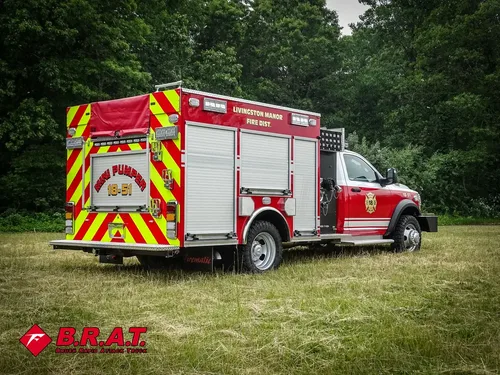 Exterior view of small fire truck showing cab, body compartments, and wheel/tire area.