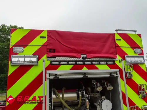 Exterior view of small fire truck showing cab, body compartments, and wheel/tire area.