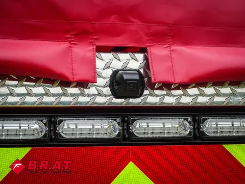 Exterior view of small fire truck showing cab, body compartments, and wheel/tire area.