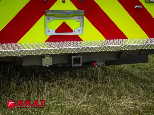 Exterior view of small fire truck showing cab, body compartments, and wheel/tire area.