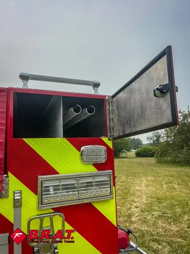 Exterior view of small fire truck showing cab, body compartments, and wheel/tire area.