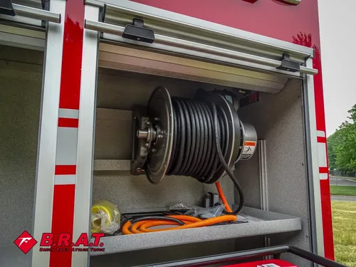 Exterior view of small fire truck showing cab, body compartments, and wheel/tire area.