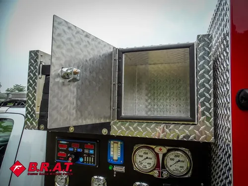 Exterior view of small fire truck showing cab, body compartments, and wheel/tire area.