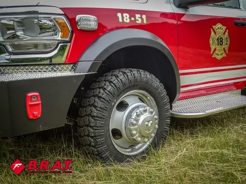 Exterior view of small fire truck showing cab, body compartments, and wheel/tire area.