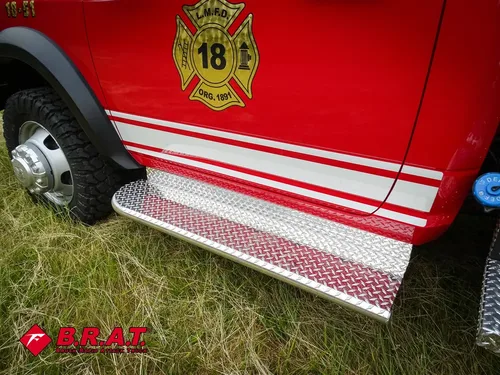 Exterior view of small fire truck showing cab, body compartments, and wheel/tire area.