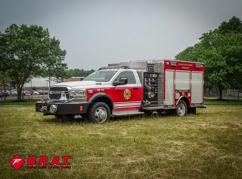Exterior view of small fire truck showing cab, body compartments, and wheel/tire area.