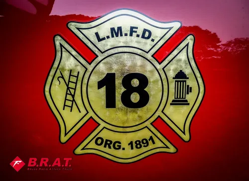 Exterior view of small fire truck showing cab, body compartments, and wheel/tire area.