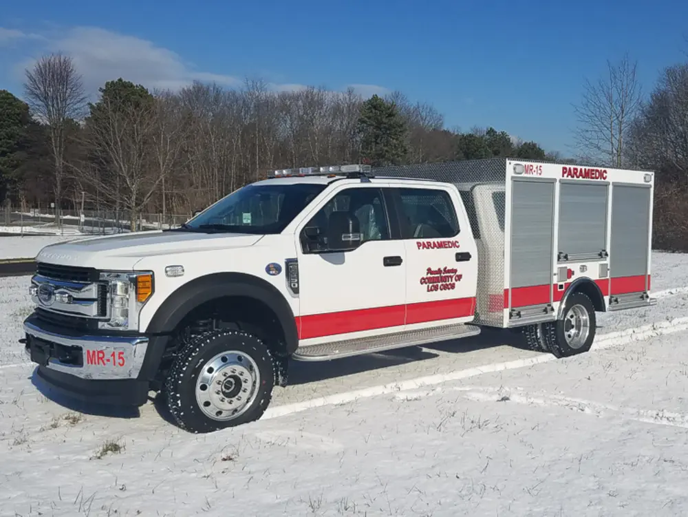 Exterior view of small fire truck showing cab, body compartments, and wheel/tire area.