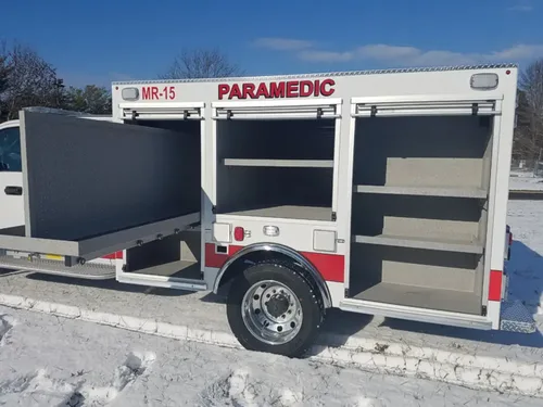 Exterior view of small fire truck showing cab, body compartments, and wheel/tire area.