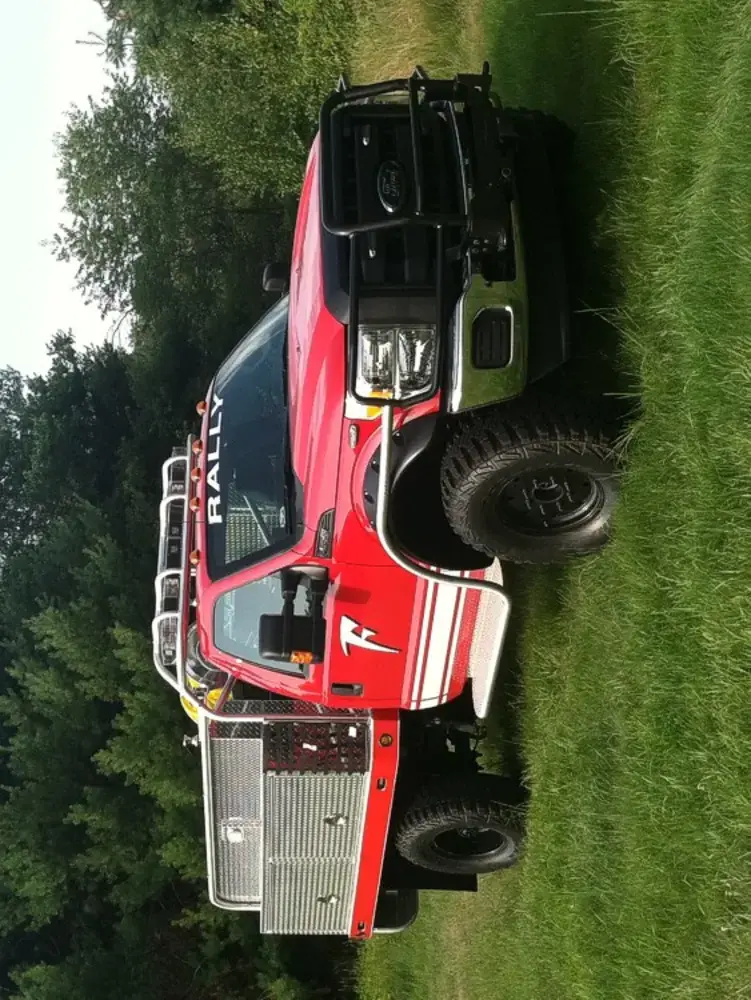 Exterior view of small fire truck showing cab, body compartments, and wheel/tire area.