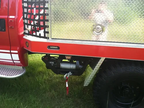 Exterior view of small fire truck showing cab, body compartments, and wheel/tire area.