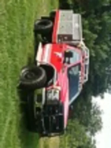 Exterior view of small fire truck showing cab, body compartments, and wheel/tire area.