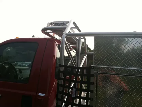 Exterior view of small fire truck showing cab, body compartments, and wheel/tire area.