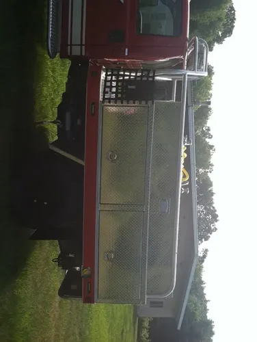 Exterior view of small fire truck showing cab, body compartments, and wheel/tire area.