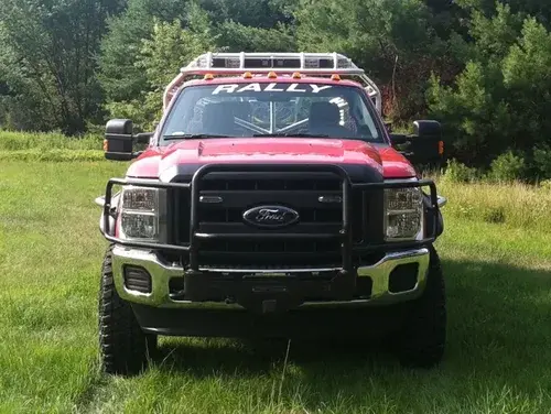 Exterior view of small fire truck showing cab, body compartments, and wheel/tire area.