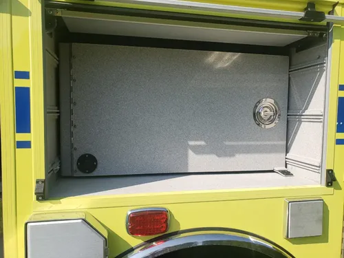 Exterior view of small fire truck showing cab, body compartments, and wheel/tire area.