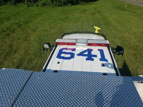 Exterior view of small fire truck showing cab, body compartments, and wheel/tire area.