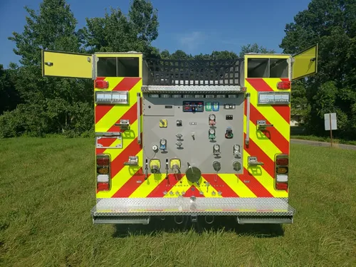 Exterior view of small fire truck showing cab, body compartments, and wheel/tire area.