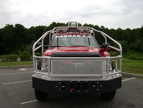 Exterior view of small fire truck showing cab, body compartments, and wheel/tire area.