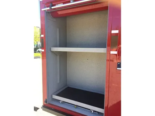 Exterior view of small fire truck showing cab, body compartments, and wheel/tire area.