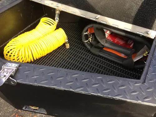 Exterior view of small fire truck showing cab, body compartments, and wheel/tire area.