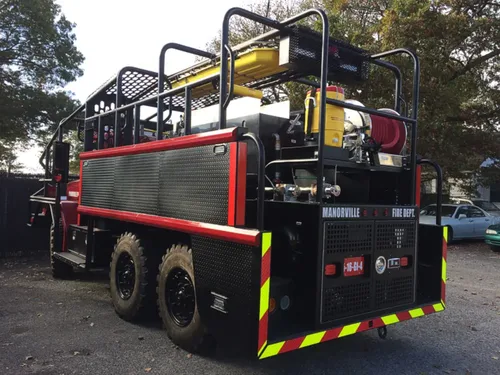 Exterior view of small fire truck showing cab, body compartments, and wheel/tire area.