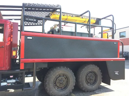 Exterior view of small fire truck showing cab, body compartments, and wheel/tire area.