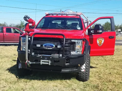 Exterior view of small fire truck showing cab, body compartments, and wheel/tire area.