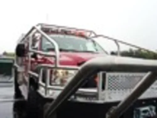 Exterior view of small fire truck showing cab, body compartments, and wheel/tire area.