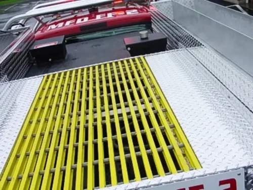 Exterior view of small fire truck showing cab, body compartments, and wheel/tire area.
