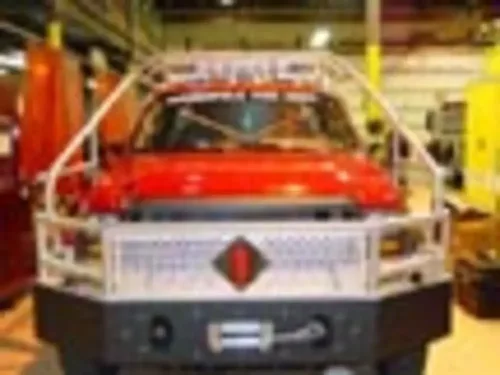 Exterior view of small fire truck showing cab, body compartments, and wheel/tire area.