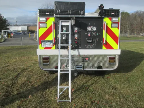 Exterior view of small fire truck showing cab, body compartments, and wheel/tire area.