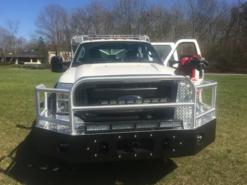 Exterior view of small fire truck showing cab, body compartments, and wheel/tire area.