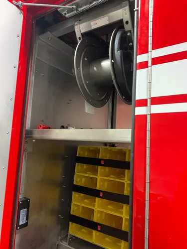 Exterior view of small fire truck showing cab, body compartments, and wheel/tire area.