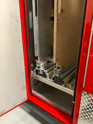 Exterior view of small fire truck showing cab, body compartments, and wheel/tire area.