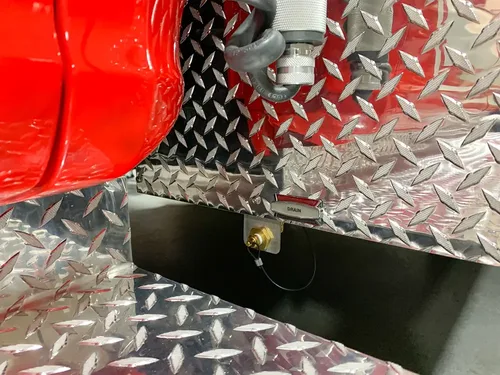 Exterior view of small fire truck showing cab, body compartments, and wheel/tire area.