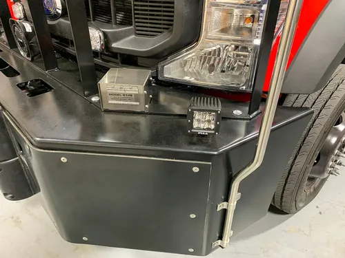 Exterior view of small fire truck showing cab, body compartments, and wheel/tire area.