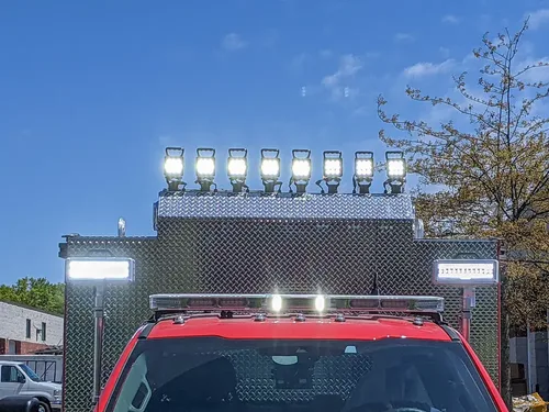 Exterior view of small fire truck showing cab, body compartments, and wheel/tire area.