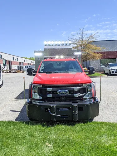 Exterior view of small fire truck showing cab, body compartments, and wheel/tire area.