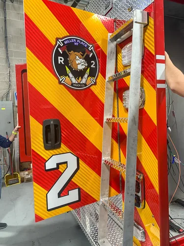 Exterior view of small fire truck showing cab, body compartments, and wheel/tire area.