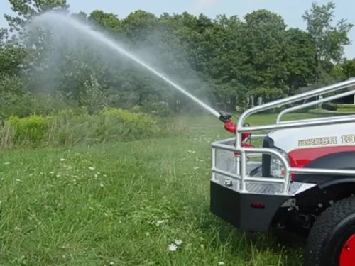 Exterior view of small fire truck showing cab, body compartments, and wheel/tire area.