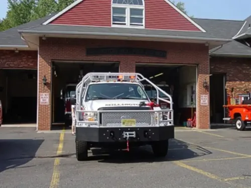Exterior view of small fire truck showing cab, body compartments, and wheel/tire area.