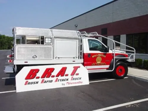 Exterior view of small fire truck showing cab, body compartments, and wheel/tire area.