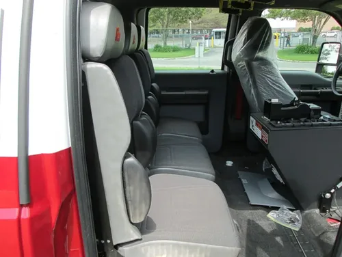 Exterior view of small fire truck showing cab, body compartments, and wheel/tire area.